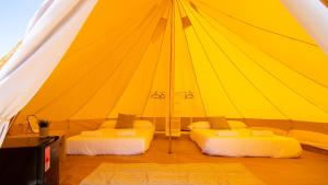 费罗尔Glamping Atlántico的大型黄色帐篷内的两张床