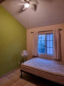 Emiliano ZapataAgusticidad en Cuernavaca的一间卧室配有一张带窗户和吊扇的床。