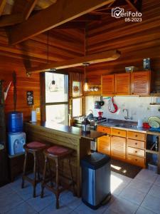 米纳斯Casa de campo la serena的厨房配有木制橱柜和带凳子的台面