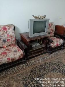 سوهاج الجديدة的客厅配有两把椅子和电视