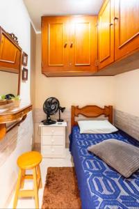 里约热内卢Quarto em casa de vila em Botafogo, Rio de Janeiro的一间卧室配有一张床、一个凳子和橱柜