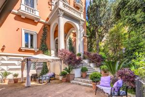 罗马Mangili Garden Hotel的房屋设有带椅子和遮阳伞的庭院