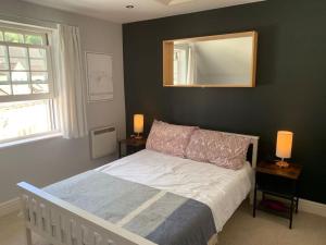 内尔斯沃思Modern loft retreat in the heart of Nailsworth的一间卧室配有一张带镜子的床和两盏灯。