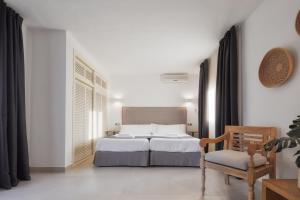 埃斯普霍斯Alojamientos Turísticos Cardona - Estudio Doble Superior的白色卧室配有床和椅子