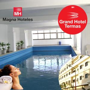 特尔马斯德里奥翁多Grand Hotel by MH的一位女士躺在一座拥有宏伟酒店帐篷标志的游泳池里