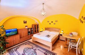 莱沃恰Historical house in the center Levoča with parking的一间卧室设有黄色的墙壁、一张床和一张桌子