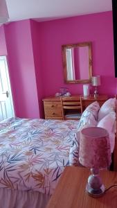 班多伦Bundoran Guesthouse的卧室设有粉红色的墙壁和一张带桌子的床