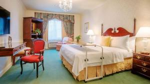 坎贝尔The Bristol Hotel Campbell San Jose的酒店客房设有一张大床和一张书桌。