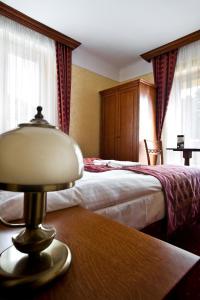 桑多梅日科罗纳酒店的酒店客房设有两张床和一张桌子上的台灯。