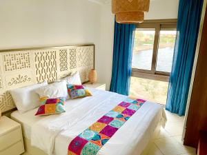 阿莱曼The Penthouse in Marassi的卧室配有带枕头的白色床和窗户。