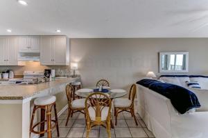 费南迪纳比奇珊瑚沙公寓 #102的厨房以及带桌椅的起居室。
