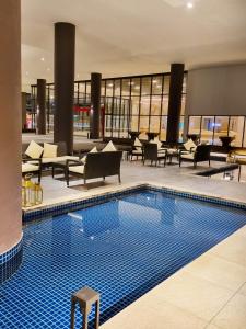 马六甲StaySuites The Apple Melaka的酒店大堂的游泳池,配有桌椅