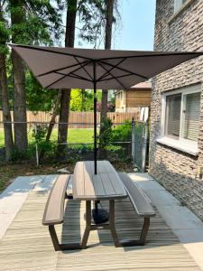 皮克灵Furnished Family Home near Toronto - Great Location Game Room - Backyard - Parking & Self Checkin的一张带两个长椅和一把雨伞的野餐桌