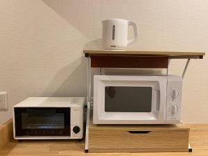 新宫市AJITO Hostel & CafeBar的桌子上设有微波炉和烤面包机。