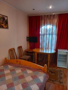 乔尔蓬阿塔гостевой дом "Бумеранг KG"的一间卧室配有一张床、一张桌子和一个窗户。