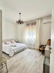 MesolaLa Villetta nel Delta的白色卧室配有一张床和一个吊灯