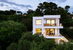 PalitPanorama Suite Dora with Jacuzzi的一座树木繁茂的山丘上的白色房子