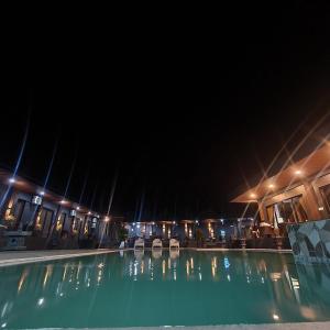 BolinaoDE PORCH的夜间游泳池,配有椅子和灯