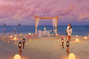鲁阿环礁You & Me Maldives的一名男子和一名女子站在海滩上,在海滩上举行婚礼