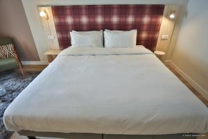 迪涅莱班Hôtel Le Refuge des Sources的一张大白色的床,位于酒店客房内