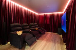 加尔米施-帕滕基兴Boutique ChaletS Alpi - Private Sauna & Cinema的剧院间配有红色窗帘和一套椅子