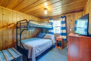 Hubbard LakeCharming Michigan Cottage with Sunroom and Lake Access的一间卧室配有双层床和一台平面电视。