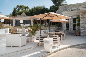 罗达Luxury Villa Hera - Beachfront的一个带桌椅和遮阳伞的庭院
