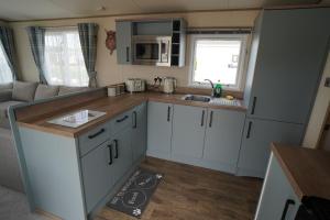 亨斯坦顿Heacham Sunset lodge Platinum van的小厨房配有白色橱柜和水槽