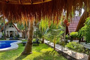 吉利阿尔Gili Land的一个带游泳池和草伞的度假庭院