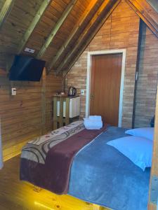 乌鲁比西Chalés Snow的木制客房内的一间卧室配有一张大床