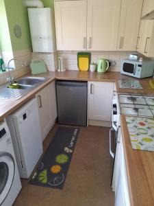 康威Bryn Castell, Conwy的厨房配有白色橱柜,厨房地毯位于地板上