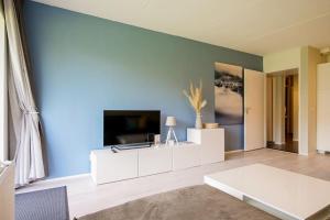 卡兰茨奥赫Beach Appartement 10 - Callantsoog的一间客厅,客厅的蓝色墙壁上配有电视
