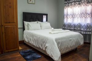 德班Gielex Guest House的卧室配有一张带白色床单和枕头的大床。