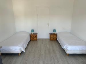 PleybenLes chambres du Bistro du Canal的配有白色墙壁和木地板的客房内的两张床