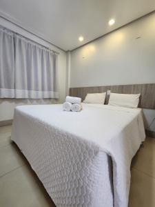 古鲁皮Oiti Hotel - By Up Hotel的卧室配有带毛巾的大型白色床