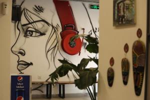 安曼Nomads Hotel的挂着一幅画女人的墙和钟