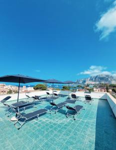 蒙德罗Mongibello Palace B&B的屋顶上带躺椅和遮阳伞的游泳池