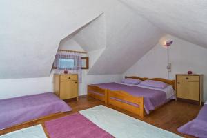 波斯蒂拉Vacation House, PARKING INCLUDED, Lovrecina的阁楼卧室配有两张床和紫色床单