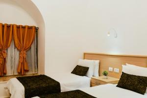 耶路撒冷William's Guest House的一间卧室设有两张床,窗户配有橙色窗帘