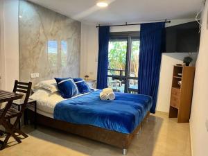 哈德拉Ahuzat Shaul Hotel Seaside的一间卧室配有一张带蓝色床单的床和一扇窗户。