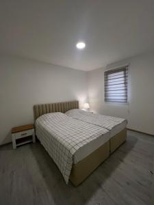 维索科Apartmani Zeleni Vrtovi的一间卧室设有一张大床和一个窗户。