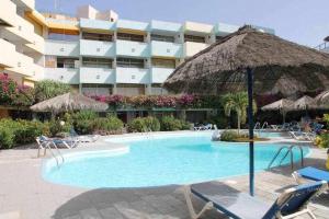 圣巴托洛梅Apartamento con piscina climatizada y vista al mar的一个带椅子和遮阳伞的游泳池以及酒店