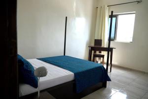 科托努Résidence des Amazones Appartement 2的一间卧室配有一张带蓝色毯子的床