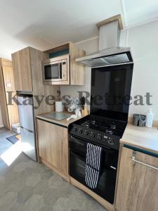 纽基Kayes Retreat Three bed caravan Newquay Bay Resort Quieter area of park的厨房配有黑炉和微波炉