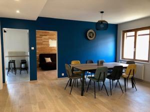 埃圭斯海姆Les trois pierres的一间设有蓝色墙壁和桌椅的用餐室