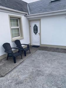 巴利瓦根JMD Lodge - Self Catering Property in the heart of The Burren between Ballyvaughan, Lisdoonvarna, Doolin and Kilfenora in County Clare Ireland的两把黑椅子坐在房子前面