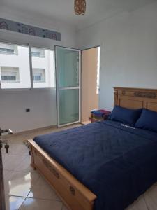 丹吉尔Rawan Appart的一间卧室配有一张带蓝色床单和窗户的床。