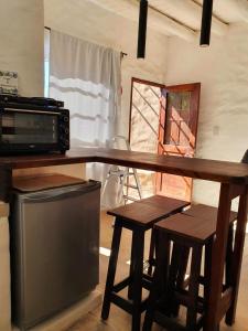 蒂尔卡拉Los tarcos Guest House LOFT TILCARA的厨房配有带微波炉和2张凳子的台面