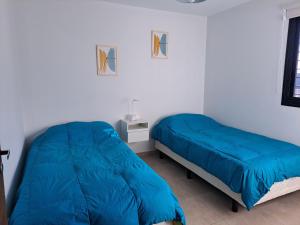 LuzuriagaMODERNO DUPLEX Con COCHERA的白色客房的两张床,配有蓝色的床单