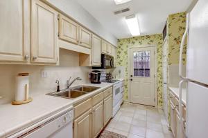 阿米莉亚岛Fairway Oaks Villa Condo的厨房配有白色橱柜、水槽和冰箱。